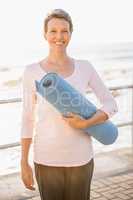 Smiling sporty woman with exercise mat