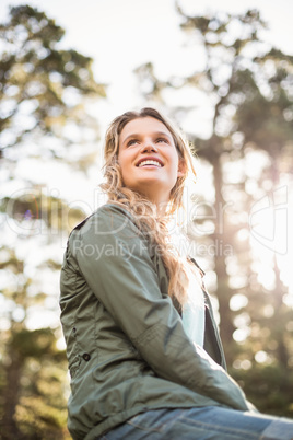 Young happy jogger sitting on rock and looking away