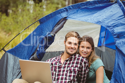 Young pretty hiker couple sitting in a tent looking at camera