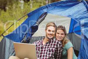 Young pretty hiker couple sitting in a tent looking at camera