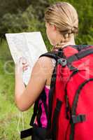 Blonde hiker with compass and reading map