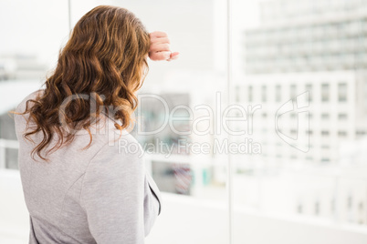 Troubled casual businesswoman leaning against window