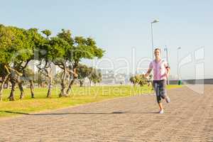 Focused sporty blonde jogging at promenade