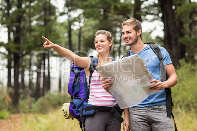 Young happy hikers pointing in the distance with a map