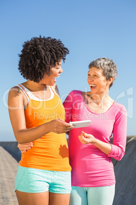 Two laughing sporty women looking at their selfies