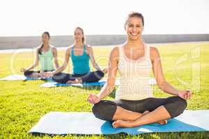 Smiling sporty brunette doing yoga with her friends
