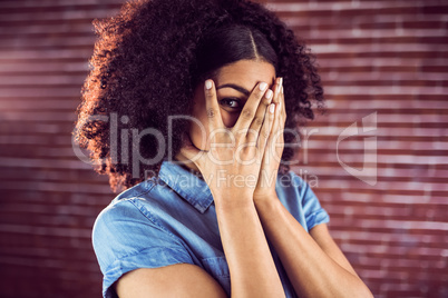 Attractive young woman hiding behind hands