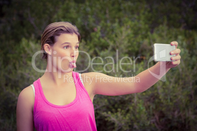 Pretty blonde athlete taking selfies with outstretched tongue