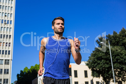 Handsome athlete jogging against blue sky