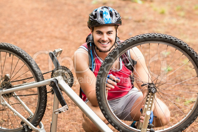 Happy handsome biker repairing bike and looking at camera