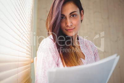 Pretty brunette reading documents beside window