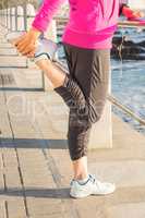 Sporty woman stretching leg at promenade