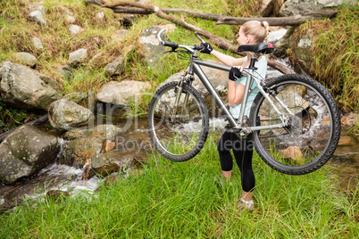 Side view of a fit woman lifting her bike