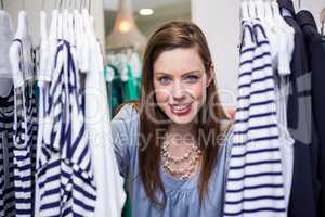 Brunette smiling through clothes rail