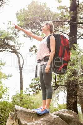 Smiling blonde hiker pointing far away