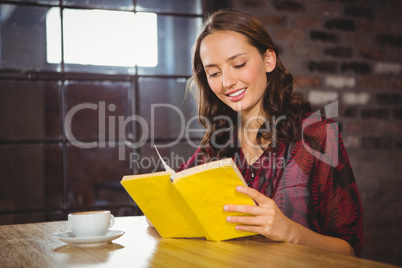 Smiling brunette turning the page of yellow book