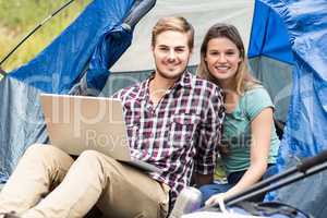 Young pretty hiker couple sitting in a tent looking at camera