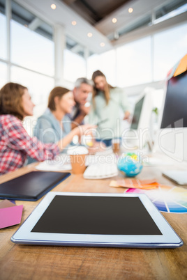 Tablet in the foreground with business people in the background