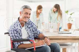Casual businessman in wheelchair with notepad