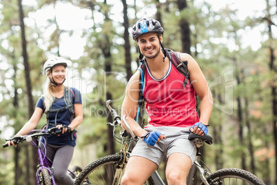 Young happy couple on bikes looking at camera