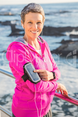 Smiling sporty woman enjoying music via headphones