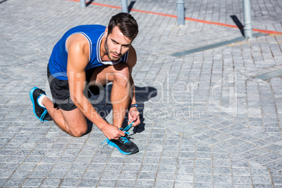 Handsome athlete tying his shoes on a sunny day