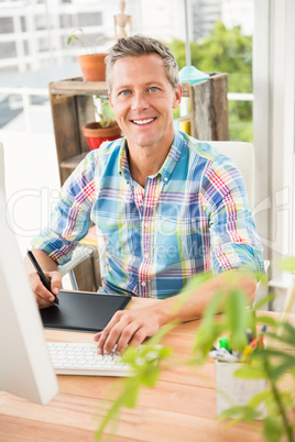 Smiling casual designer using computer and digitizer