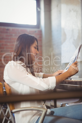 Pretty businesswoman reading newspaper