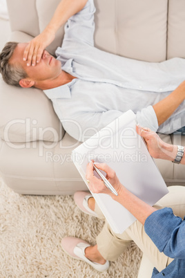 Depressed man lying on couch and talking to therapist