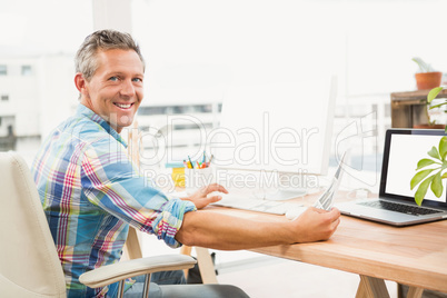 Smiling casual designer editing photos with computer