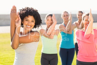 Smiling sporty women doing eagle pose in yoga class
