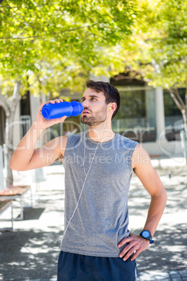 Handsome runner drinking water with hands on hips