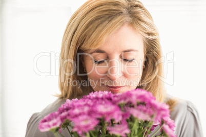Casual businesswoman smelling at flowers