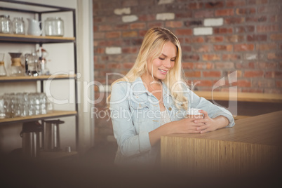 Smiling blonde sitting and holding take-away cup