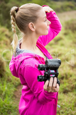Female hiker looking away and holding binoculars
