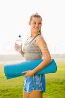 Sporty blonde holding exercise mat and water bottle