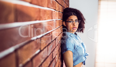 Attractive hipster leaning against red brick background