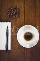 Cup of coffee and notepad with pen
