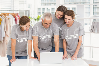 Smiling volunteers using laptop together