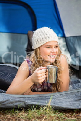 Pretty blonde camper smiling and lying in tent