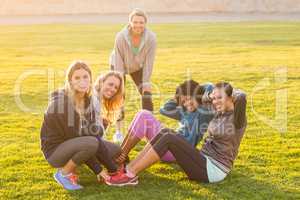 Smiling sporty women doing sit ups during fitness class