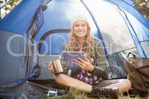 Pretty blonde camper using tablet and holding cup