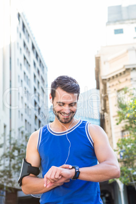 Smiling handsome athlete setting heart rate watch