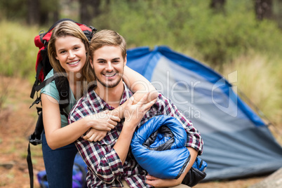 Portrait of a young pretty hiker couple holding a sleeping bag a
