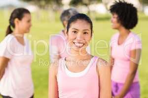 Smiling woman wearing pink for breast cancer in front of friends