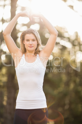 Pretty young jogger shaping heart with arms