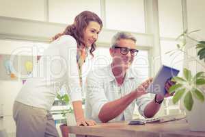 Two smiling casual designers working with tablet