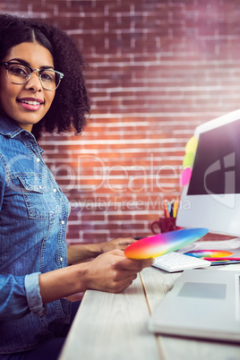 Casual female designer smiling and holding colour chart