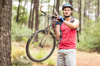 Happy handsome biker holding bike and looking at camera