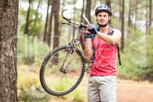 Happy handsome biker holding bike and looking at camera